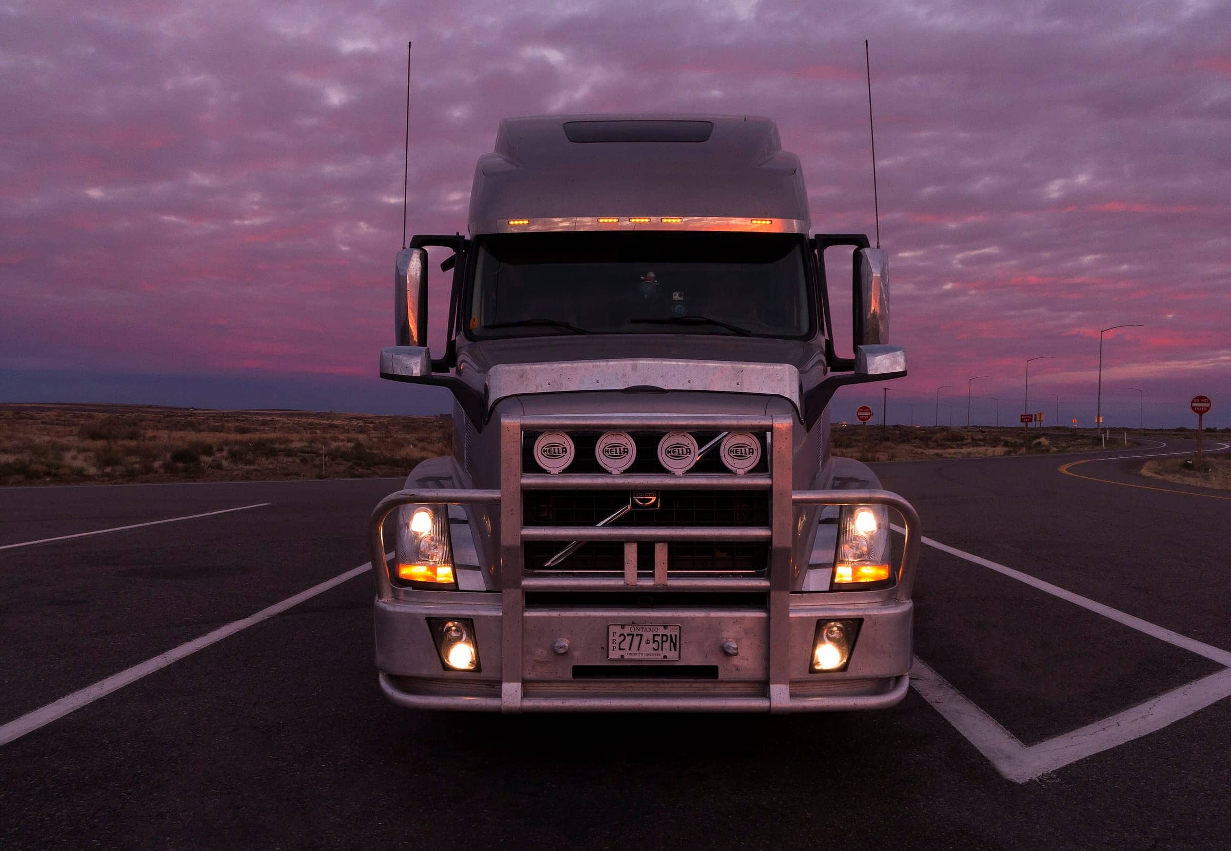 Front view of a long-haul tractor with headlights on at dusk